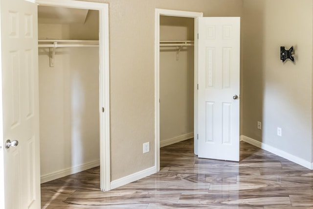 unfurnished bedroom featuring multiple closets and baseboards