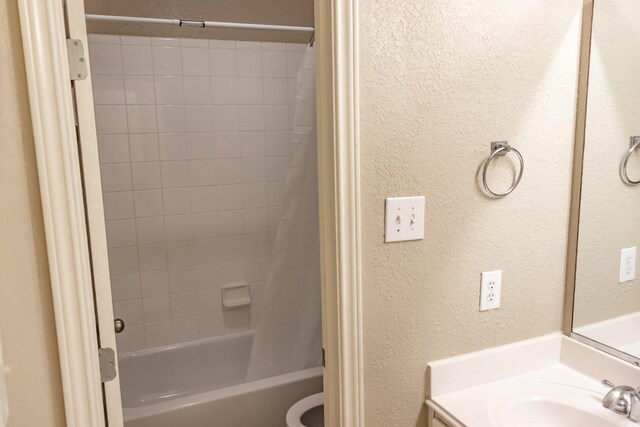 bathroom featuring toilet, a textured wall, shower / bath combo, and vanity