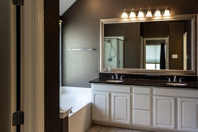 bathroom with tile patterned floors, a tub to relax in, and vanity