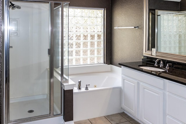 full bath with a textured wall, a whirlpool tub, tile patterned flooring, vanity, and a shower stall