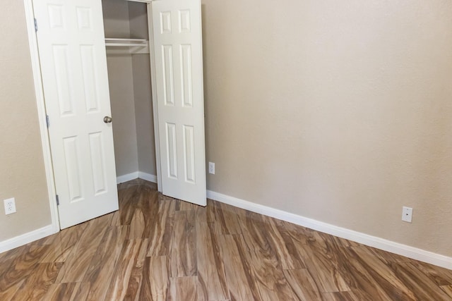 unfurnished bedroom featuring a closet, wood finished floors, and baseboards