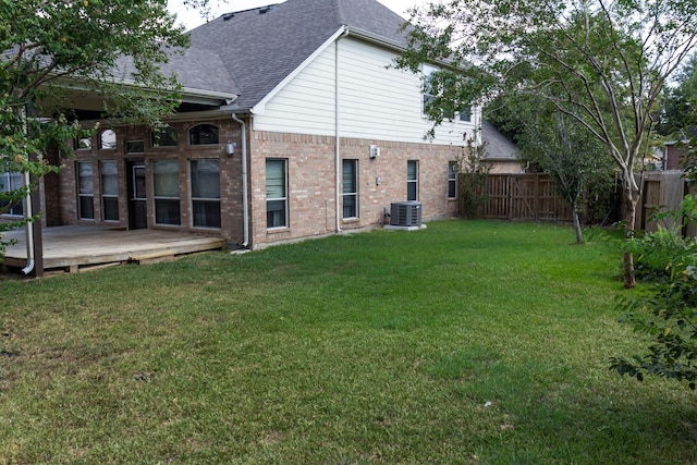 rear view of property with roof with shingles, fence, a yard, central AC, and brick siding