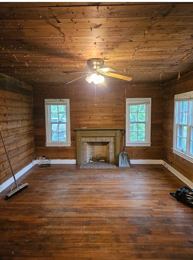 unfurnished living room with dark wood-type flooring, ceiling fan, wooden ceiling, and wood walls