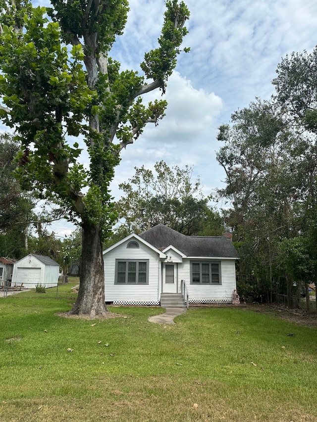 view of front of property featuring a garage, an outdoor structure, and a front yard