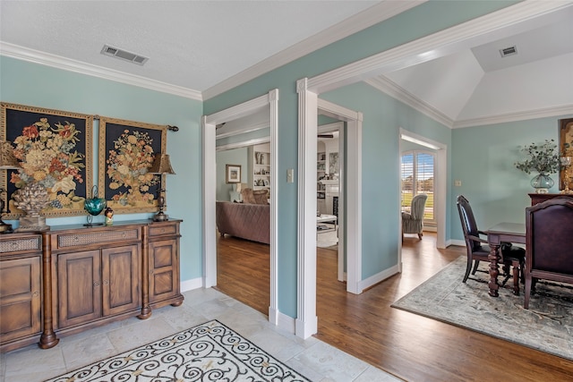 interior space featuring ornamental molding, vaulted ceiling, and light hardwood / wood-style floors