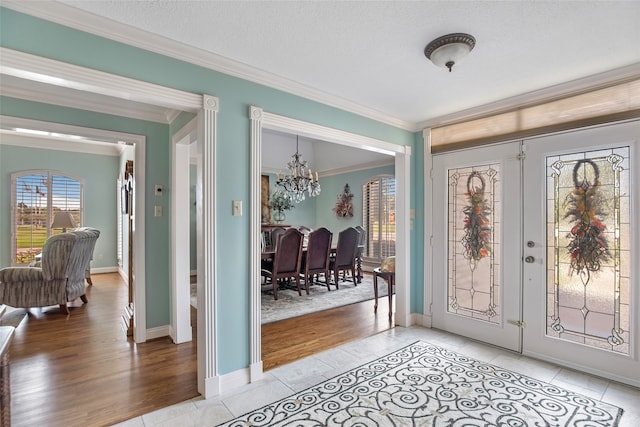 foyer featuring light hardwood / wood-style floors, ornamental molding, a textured ceiling, and a chandelier