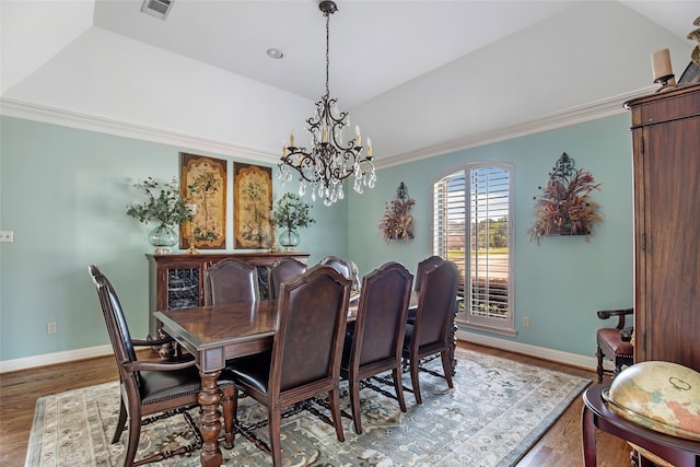 dining area featuring ornamental molding, a chandelier, hardwood / wood-style flooring, and lofted ceiling