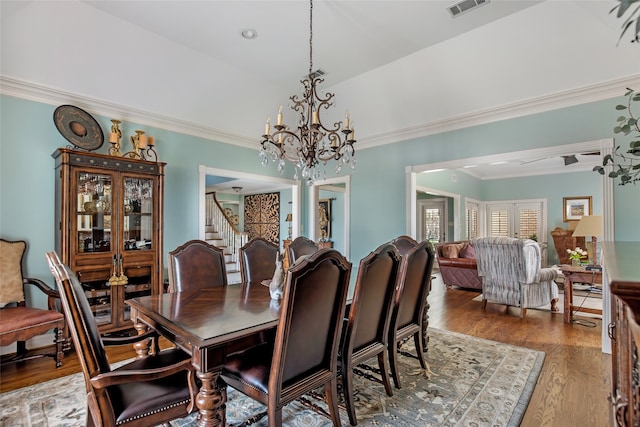 dining area with ornamental molding, an inviting chandelier, and hardwood / wood-style floors