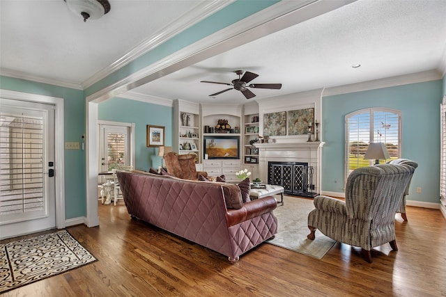 living room with crown molding, built in features, dark hardwood / wood-style flooring, a textured ceiling, and ceiling fan