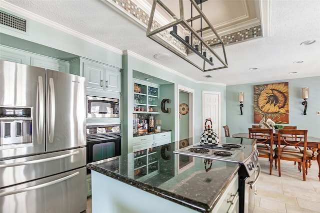 kitchen featuring appliances with stainless steel finishes, a textured ceiling, a center island, white cabinetry, and dark stone countertops