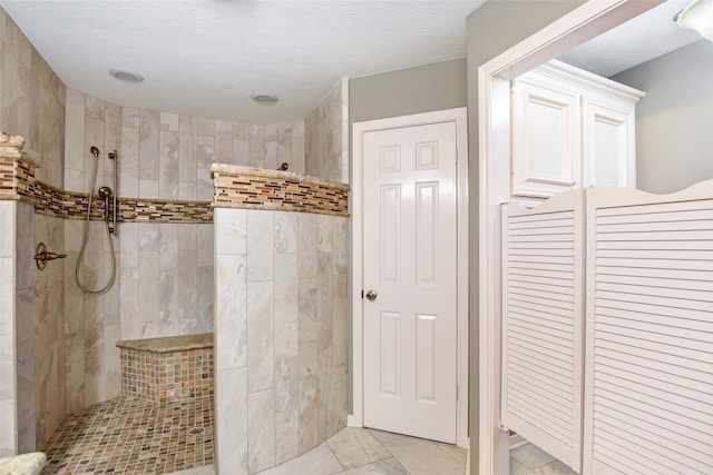 bathroom with a tile shower and a textured ceiling