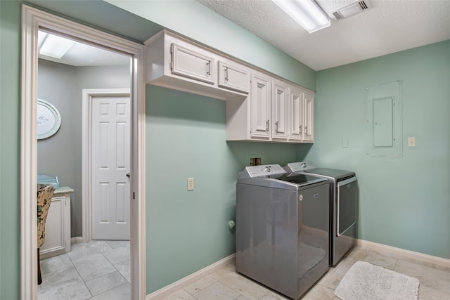 laundry area with independent washer and dryer, a textured ceiling, electric panel, and cabinets