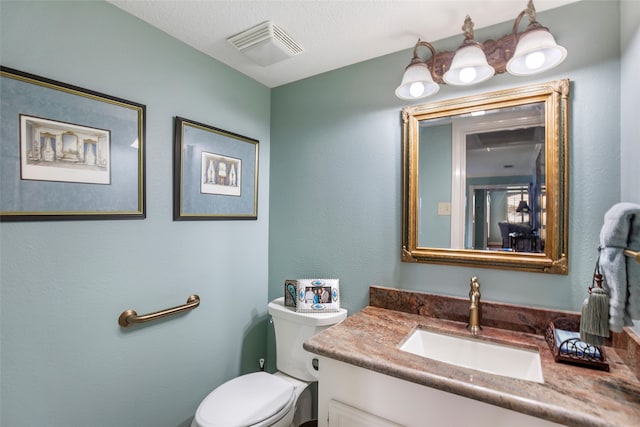 bathroom featuring vanity, a textured ceiling, and toilet