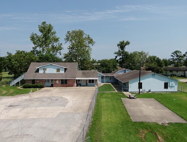 view of front of home with driveway, fence, a front lawn, and brick siding