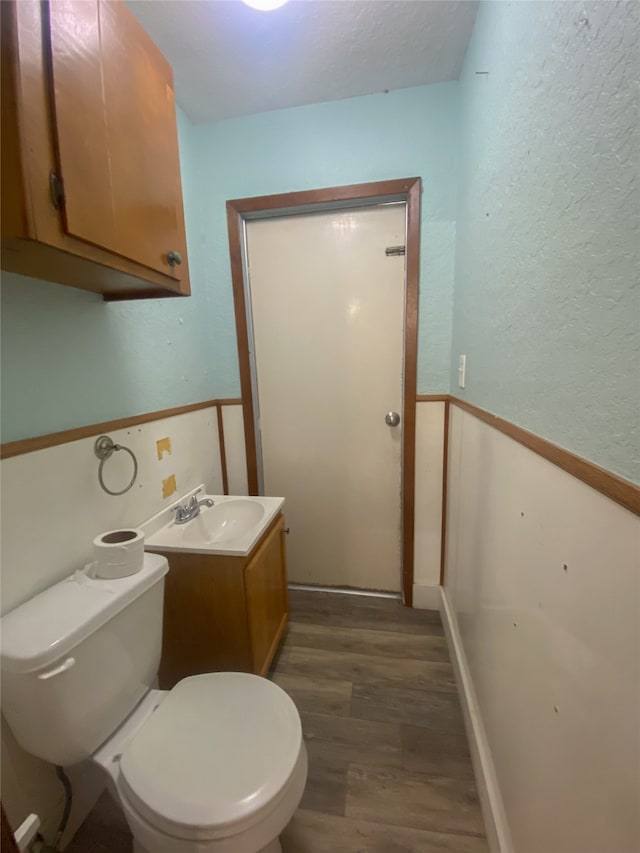 bathroom with hardwood / wood-style flooring, toilet, and vanity