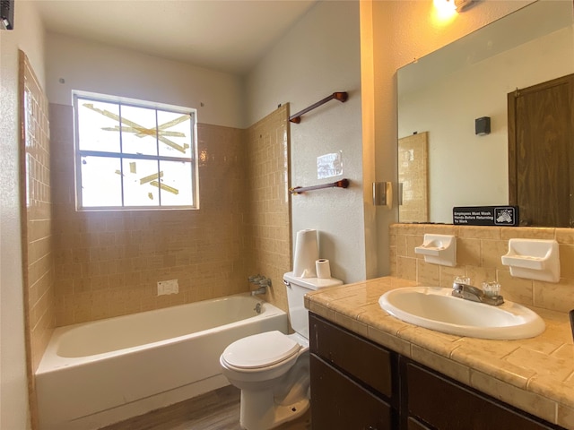 full bathroom featuring hardwood / wood-style floors, tiled shower / bath, decorative backsplash, vanity, and toilet