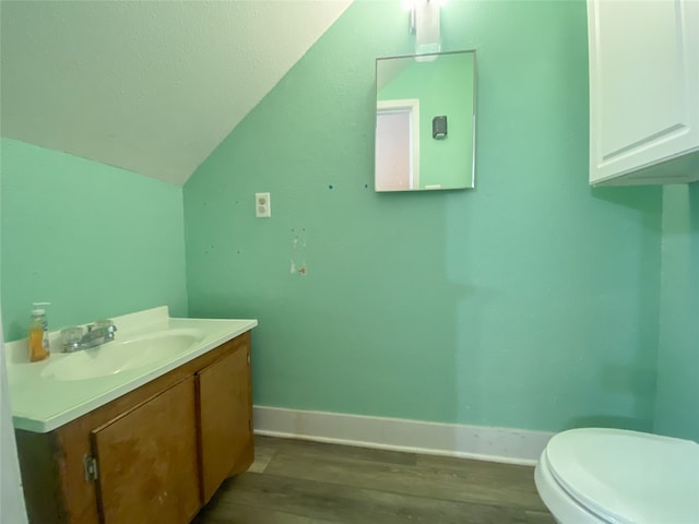 bathroom featuring hardwood / wood-style flooring, toilet, vanity, and lofted ceiling