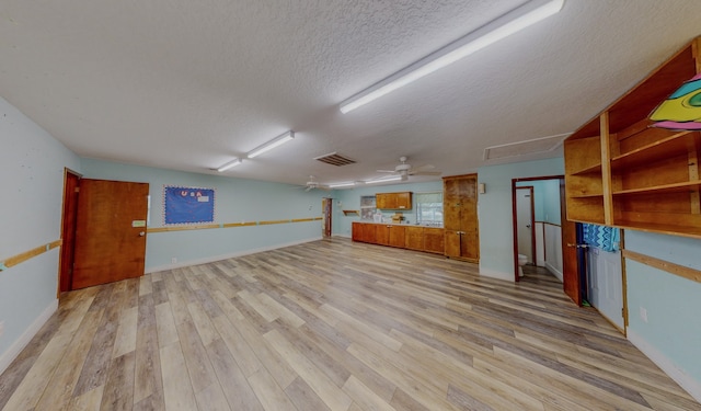 basement featuring ceiling fan, light hardwood / wood-style flooring, and a textured ceiling