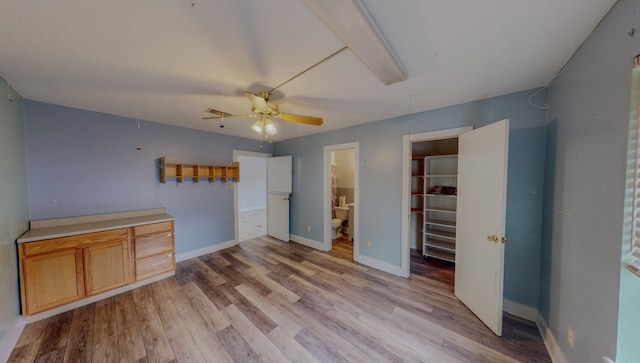 unfurnished bedroom featuring light wood-type flooring, connected bathroom, ceiling fan, and a closet