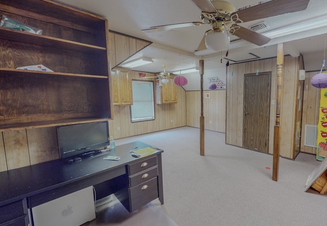 unfurnished office featuring wood walls, ceiling fan, and light colored carpet