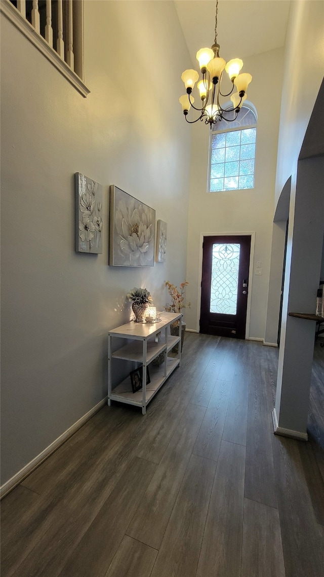 entrance foyer with a chandelier, a towering ceiling, and dark wood-type flooring