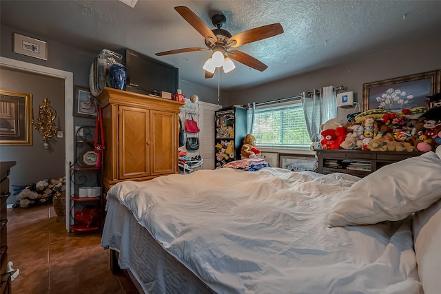 bedroom with ceiling fan, a textured ceiling, and tile patterned floors