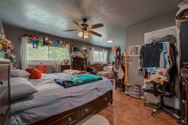 bedroom featuring ceiling fan, a textured ceiling, and light tile patterned floors