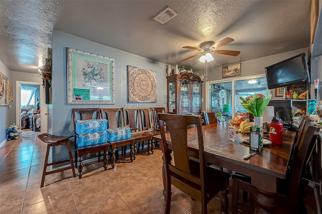 tiled dining area featuring a textured ceiling and ceiling fan