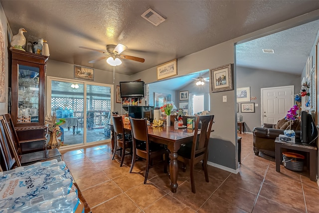 dining space featuring ceiling fan, vaulted ceiling, a textured ceiling, and tile patterned floors