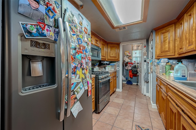 kitchen featuring tile countertops, light tile patterned floors, and stainless steel appliances