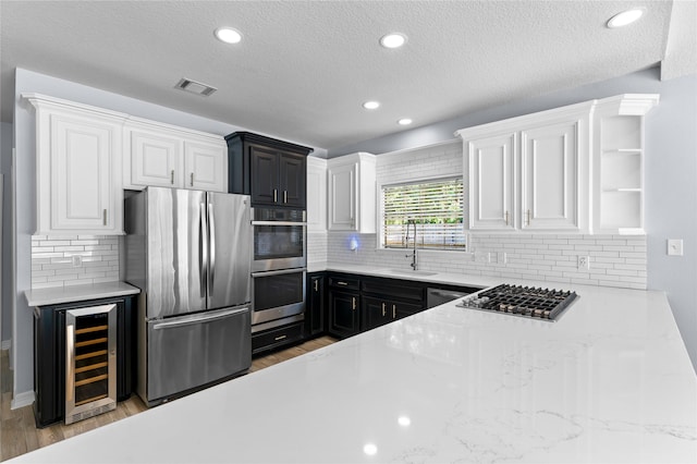 kitchen with beverage cooler, white cabinetry, sink, and appliances with stainless steel finishes