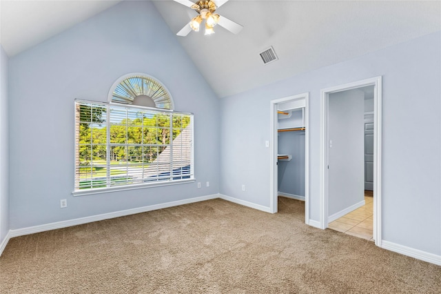 unfurnished bedroom featuring light carpet, high vaulted ceiling, ceiling fan, a spacious closet, and a closet