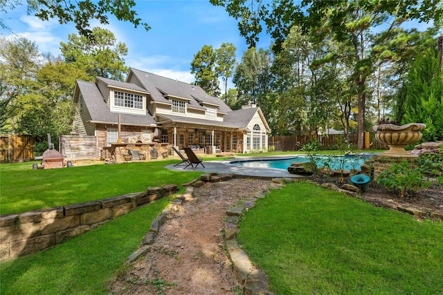 back of house featuring a fenced in pool, a yard, a patio, and an outdoor kitchen