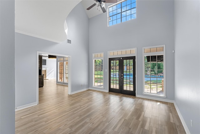 interior space featuring ceiling fan, french doors, light hardwood / wood-style floors, and a high ceiling