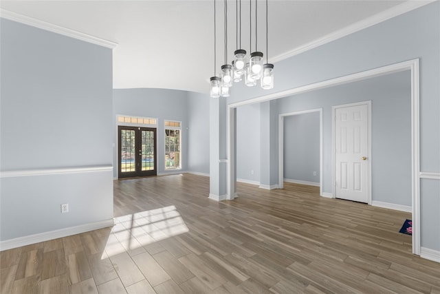 unfurnished dining area with hardwood / wood-style flooring, a notable chandelier, ornamental molding, and french doors