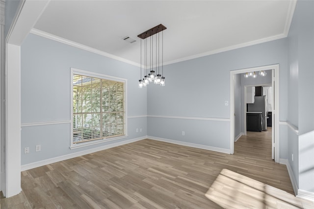 spare room with a notable chandelier, light hardwood / wood-style floors, and ornamental molding