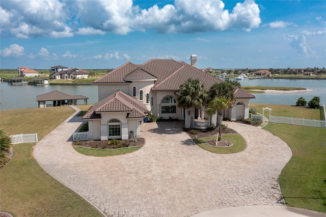 153 E Tuscany Way, Port O Connor, TX 77979 - mediterranean / spanish-style home with curved driveway, a tiled roof, a water view, and stucco siding