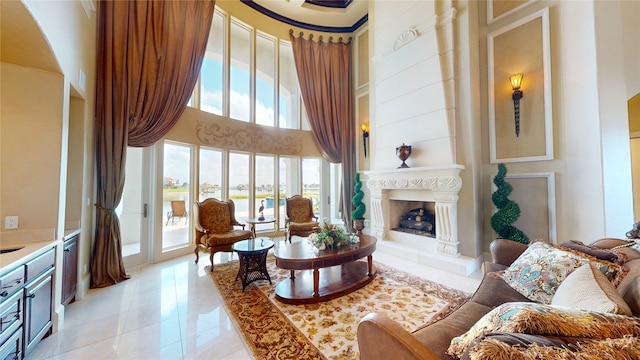 tiled living room featuring a towering ceiling, plenty of natural light, and a high end fireplace