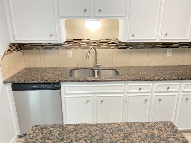 kitchen featuring white cabinets, dishwasher, sink, dark stone counters, and tasteful backsplash