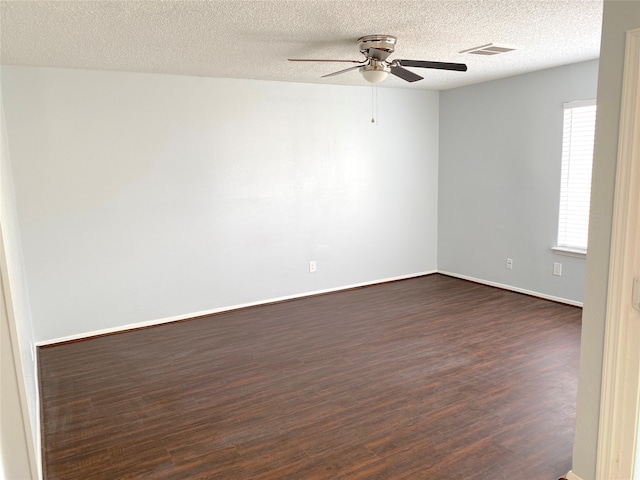 empty room featuring dark wood-type flooring, a textured ceiling, and ceiling fan