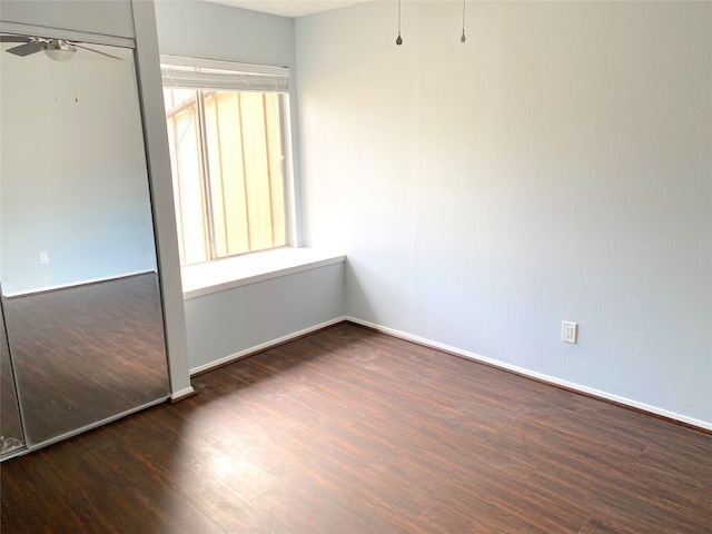 unfurnished room featuring dark wood-type flooring and ceiling fan