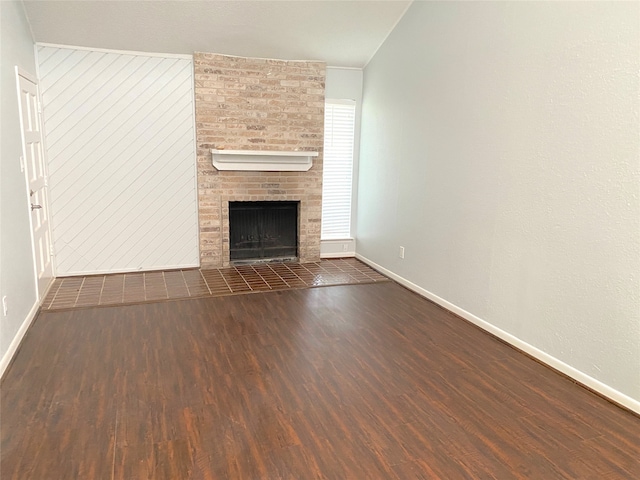 unfurnished living room with dark wood-type flooring and a brick fireplace