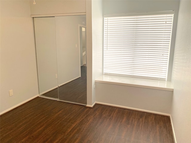 unfurnished bedroom with a closet and dark hardwood / wood-style floors