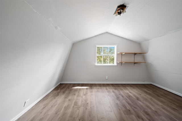 additional living space with baseboards, lofted ceiling, and wood finished floors