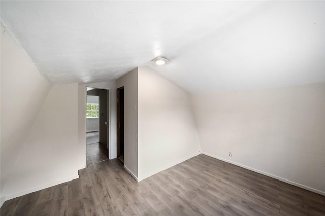 bonus room with baseboards, wood finished floors, and vaulted ceiling