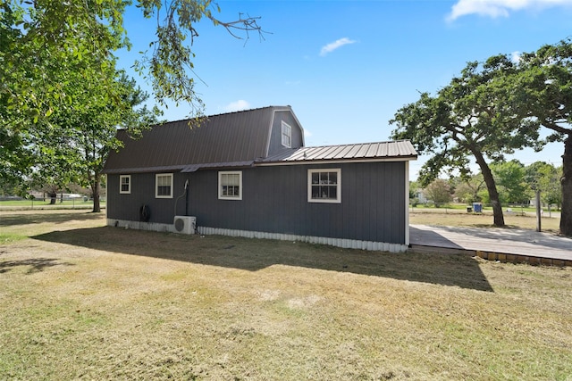 back of property featuring ac unit, metal roof, and a lawn