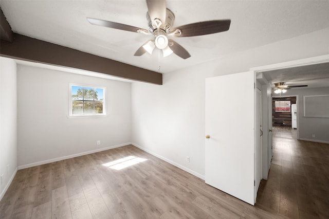 empty room with baseboards, a ceiling fan, and wood finished floors