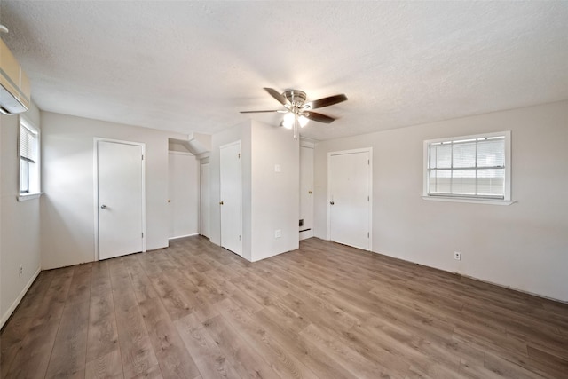 unfurnished bedroom featuring two closets, a textured ceiling, wood finished floors, and ceiling fan