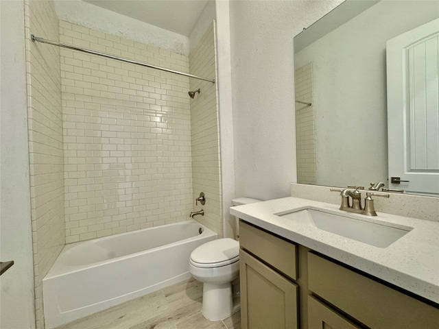 full bathroom with vanity, tiled shower / bath, wood-type flooring, and toilet