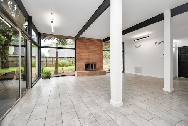 unfurnished living room featuring light tile patterned floors, a fireplace, beam ceiling, and brick wall